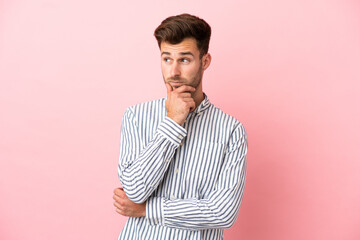 Young caucasian handsome man isolated on pink background thinking an idea while looking up
