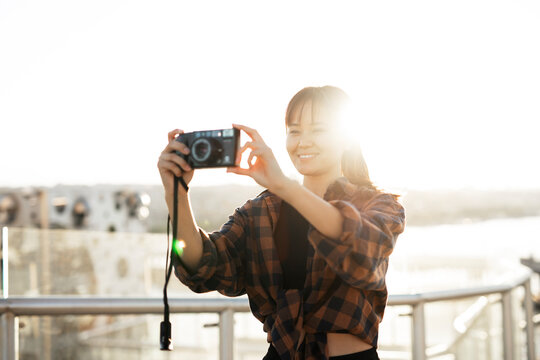 Attractive tourist with a camera. Beautiful woman with camera taking photos of beautiful location.