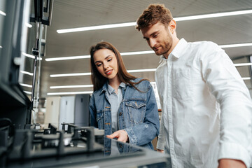 Young couple choosing new gas stove in home appliances store