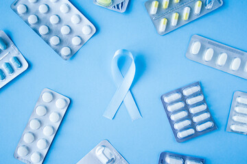 Blue ribbon symbol of prostate cancer with many pills and drugs clusters on bright background....