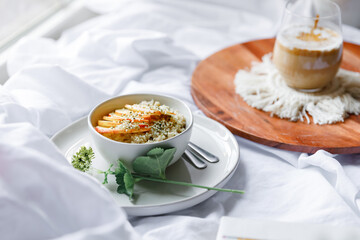 Dalgona coffee with apple oatmeal breakfast on white cozy bed