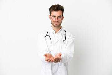 Young doctor caucasian man over isolated on white background wearing a doctor gown and holding something