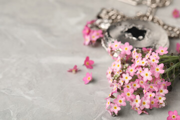 Beautiful Forget-me-not flowers and pocket watch on grey table, closeup. Space for text