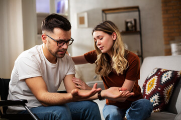 Young sad man in a wheelchair. Girlfriend comforting her sad boyfriend.