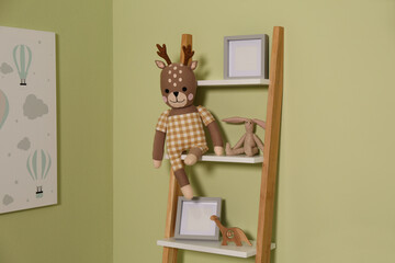Wooden decorative ladder with toys and frames near green wall. Interior design