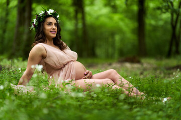Naklejka na ściany i meble Beautiful latino pregnant woman in the forest