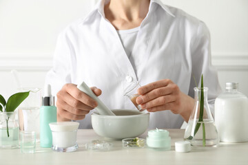 Scientist making cosmetic product at table in laboratory, closeup