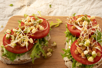 Sandwiches with cream cheese, tomatoes and bean sprouts on the wooden board