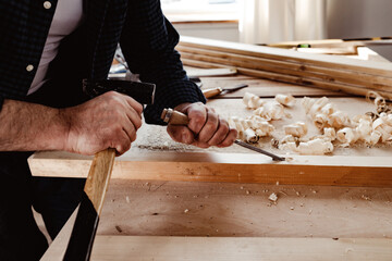 Hands of a carpenter working with chisel and hammer