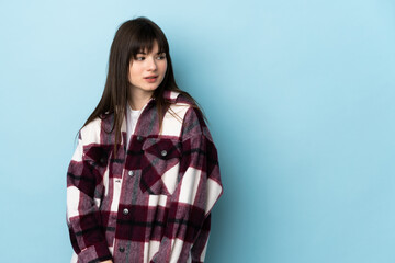 Fototapeta premium Teenager Ukrainian girl isolated on blue background having doubts while looking side