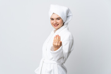 Teenager girl in a bathrobe isolated on white background inviting to come with hand. Happy that you came