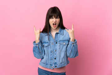 Young Ukrainian woman isolated on pink background making horn gesture
