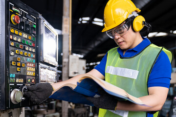 Asian engineer male worker maintaining electronics of machine at the industry factory. Factory worker check or maintenance CNC machine in industry factory