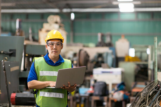 Portrait Of Asian Male Factory Worker Working With Laptop Computer In The Industry Factory. Male Engineer Working With Laptop Computer In The Factory