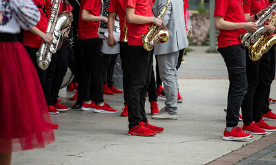 group of musicians, orchestra in red t-shirts and sneakers playing the saxophone
