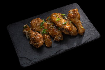 fried teriyaki chicken wingson a dark slate, stone or concrete background