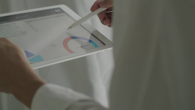 Close-up hands businessman holding tablet and using tablet checking chart statistics data report at the office.