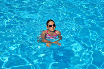 Real adorable girl relaxing in swimming pool