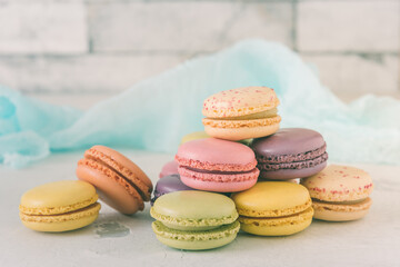 Stacked pastel colored french macarons in front of a white wall