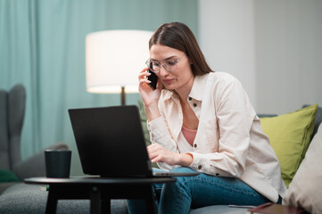 During the break of the working day, the manager girl is talking on the phone, sitting on the couch