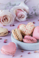 Heart shaped sweet macarons and roses in pastel colors on a pink base. A delicious dessert or gift...