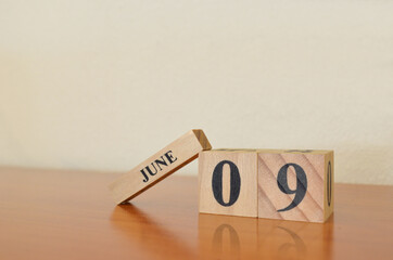 June 9, Date design with calendar cube on wooden table and white background.	
