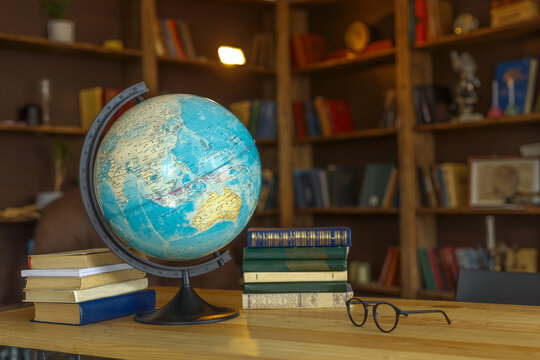 school globe stands on the table next to textbooks on the background of bookshelves, school background for photos
