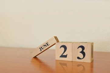 June 23, Date design with calendar cube on wooden table and white background.	
