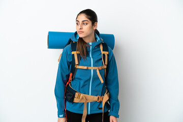 Young mountaineer man with a big backpack over isolated background looking to the side