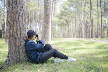 Fototapeta premium woman taking picture vintage camera while sitting on green grass under the tree in the garden