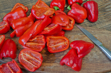 Raw red bell pepper sliced into halves on a wooden background.