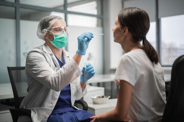 Using a cotton swab, the laboratory assistant takes the contents of the nasopharynx from the client to detect the coronavirus