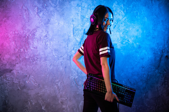 Female Esports Gamer Posing With A Gaming Gear In Neon Light. Streamer Girl Standing With A Gaming Keyboard.