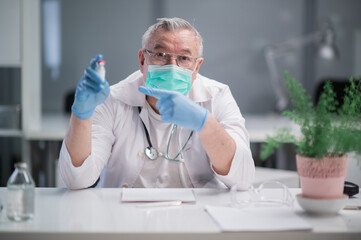 A male doctor with gray hair recommends a new vaccine against the virus to a patient who is going to get an injection as part of the covid-19 vaccination program