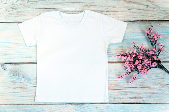 White t-shirt mockup on wooden background, top view, stock photo