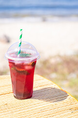 ice drink red lemonade soda on the beach cherry or strawberry fresh juice, sea coast shore, summer surf wave background refreshing relax positive mood vacation top view