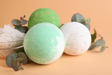 Colorful bath bombs, salt and eucalyptus branches on beige background, closeup
