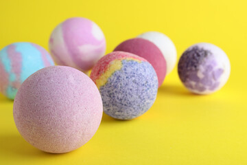 Colorful bath bombs on yellow background, closeup