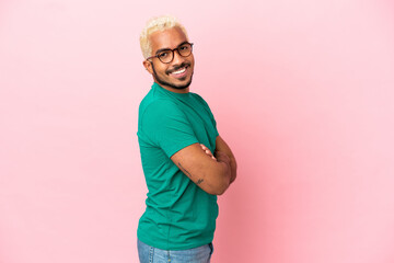 Young Colombian handsome man isolated on pink background with arms crossed and looking forward