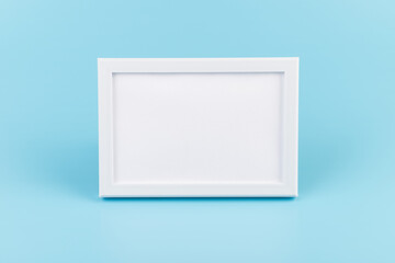 Rectangular blank white picture frame on the blue  background. mockup