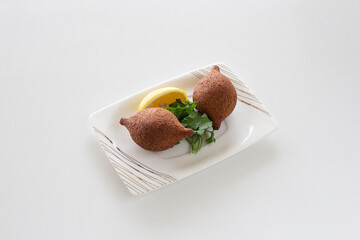 Stuffed meatballs with Turkish Style on white plate with gold stripes garnished with lemon and parsley.
