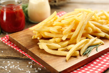 Delicious french fries served on wooden table, closeup