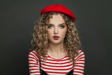 Portrait of nice french model woman with curly hair in red beret on black background