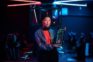 Fototapeta na wymiar An experienced asian gamer shows a gaming keyboard and talks about its advantages
