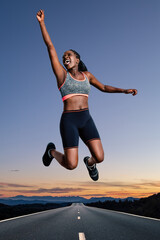 Victorious young shouting  african female athlete  jumping  outdoors.