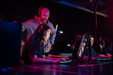 Esports team training camp in computer club with coach, caucasian guy and asian girl