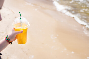 ice drink juice yellow lemonade on the beach sea coast shore, orange fresh summer surf wave background refreshing drink relax positive mood vacation top view