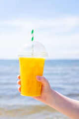 ice drink juice yellow lemonade on the beach sea coast shore, orange fresh summer surf wave background refreshing drink relax positive mood vacation top view