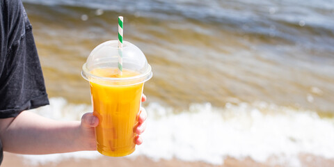 ice drink juice yellow lemonade on the beach sea coast shore, orange fresh summer surf wave background refreshing drink relax positive mood vacation top view
