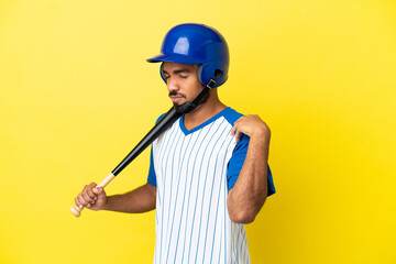 Young Colombian latin man playing baseball isolated on yellow background suffering from pain in shoulder for having made an effort